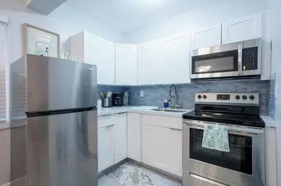 a kitchen with white cabinets and a stainless steel refrigerator at The Surf Hollywood Beach in Hollywood