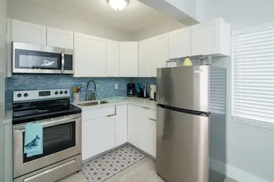a kitchen with white cabinets and a stainless steel refrigerator at The Surf Hollywood Beach in Hollywood