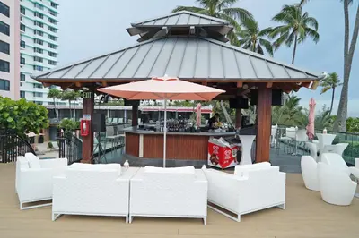 a gazebo with a bar with white chairs and an umbrella at Deluxe Apartments by South Florida Vacations in Miami Beach