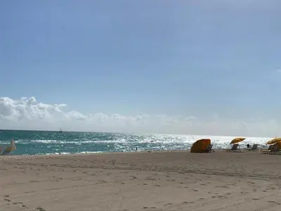 a beach with chairs and umbrellas and the ocean at Sun Sand and Love - Lovely 2 Beds, 2 Bath Condo in Miami Beach