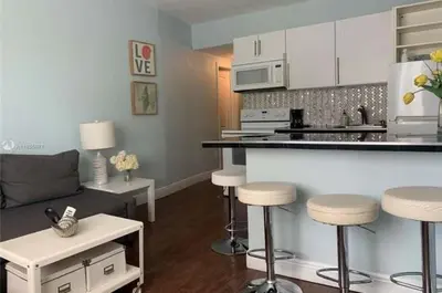 a living room with a kitchen and bar with stools at Sun Sand and Love - Lovely 2 Beds, 2 Bath Condo in Miami Beach