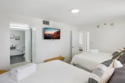 a white bedroom with two beds and a bathroom at Beautiful 3 bedroom apartment in Brickell Miami in Miami