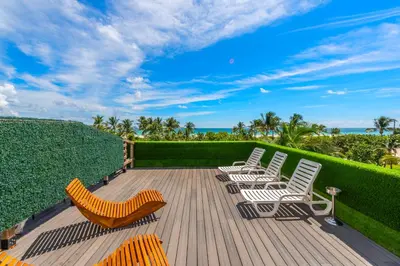a deck with chairs and the ocean in the background at SOBE suites in Miami Beach in Miami Beach