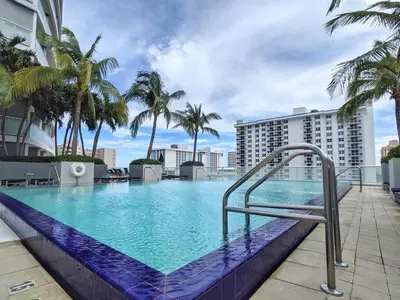 a swimming pool with palm trees and a building at WVR Vacation Residences 1707 in Fort Lauderdale
