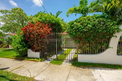 a gate in a yard with bushes and trees at Entire private Beautiful 2 Bedroom plus Den House with gated front&back yard and Free parking 10min drive to Miami Beach in Miami