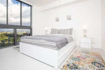 a white bedroom with a large bed and large windows at Luxury Studio Apartment in Downtown Doral in Miami