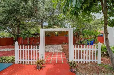 a white gate leading into a yard with a red fence at Private Room near Miami Airport - Free parking - 01 in Miami