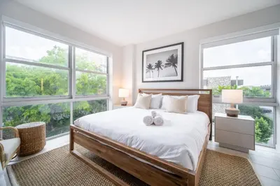 a bedroom with a large bed with windows at Tucker at Palmer Dadeland Miami in Miami