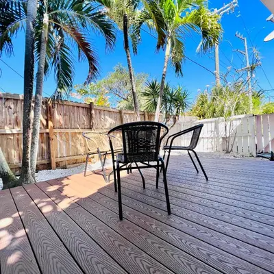 two chairs on a deck with palm trees and a fence at CocoBay 2BR Condos Near Beach, Galleria Mall, Wilton Manors, Cruise Port in Fort Lauderdale