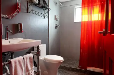 a bathroom with a toilet and a sink and a red shower curtain at Hotel Gaythering - Gay Hotel - All Adults Welcome in Miami Beach