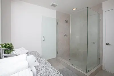 a glass shower stall in a bathroom with a couch at Luxury 1BD/1BT Apartment in Downtown Doral in Miami