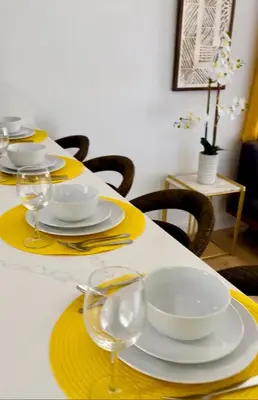 a table with yellow and white plates and wine glasses at Beautiful Casita with King Bed and private patio Close to Calle 8, MIA Airport, Coral Gables in Miami