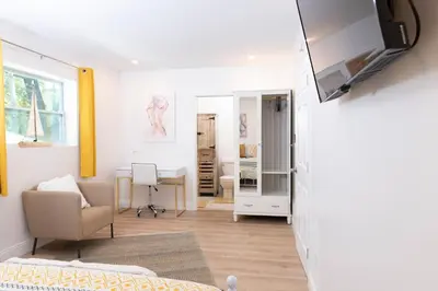 a living room with a bed and a tv on a wall at Beautiful Casita with King Bed and private patio Close to Calle 8, MIA Airport, Coral Gables in Miami