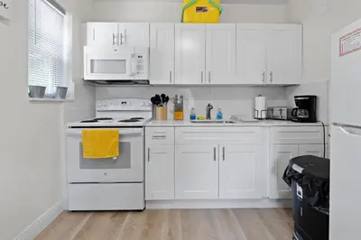 a white kitchen with white appliances and white cabinets at Enchanting cozy Apartment 10 min away from airport, Calle 8, Brickell, Coral Gables, the beach and more! in Miami