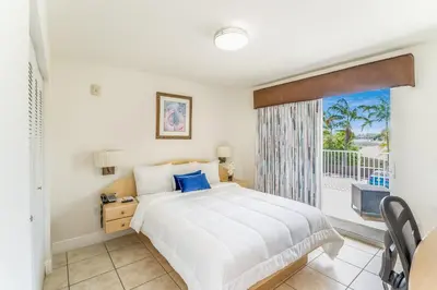 a bedroom with a white bed and a balcony at South River Suites in Medley