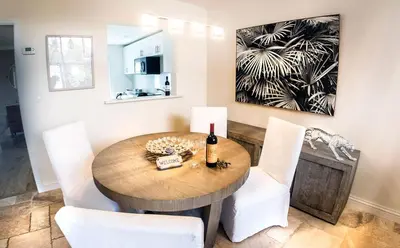 a dining room with a wooden table and white chairs at Villas at St James Place UNIT F, Luxury, Pet Friendly in Miami
