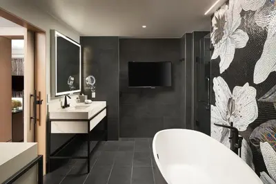 a bathroom with a tub and a sink and a tv at Loews Coral Gables Hotel in Miami