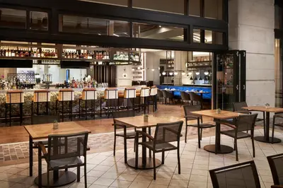 a restaurant with tables and chairs and a bar at Loews Coral Gables Hotel in Miami