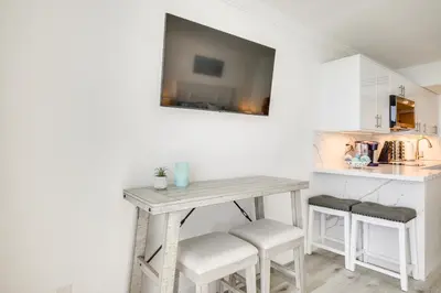 a table and stools with a television on a wall at Sunny Isles Beach Retreat with Resort Perks! in Miami Beach