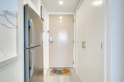 a white hallway with a door leading to a refrigerator at Sunny Isles Beach Retreat with Resort Perks! in Miami Beach