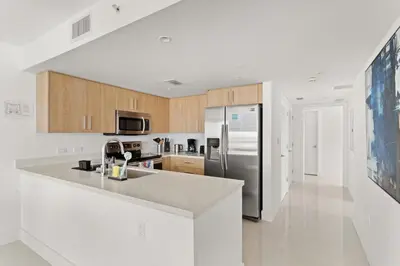 a kitchen with a stainless steel refrigerator and wooden cabinets at Bay Harbor One Vacation in Miami Beach