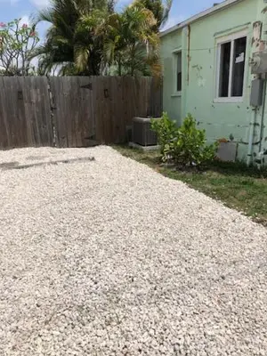 a gravel driveway next to a fence and a house at Modern Spanish Villa- Pool- By River-Tropical !!! in Fort Lauderdale