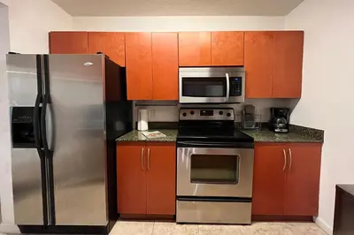 a kitchen with stainless steel appliances and wooden cabinets at 4 bed full condo in Miami with skyline & sea view in Miami