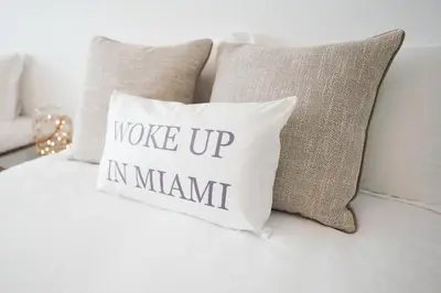 a pillow with the words woke up ininant sits on a bed at 4 bed full condo in Miami with skyline & sea view in Miami