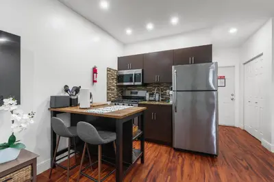 a kitchen with a stainless steel refrigerator and a table at The Pearl Beachside Apartments on Hollywood Beach in Hollywood