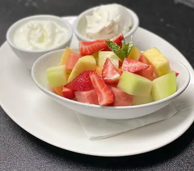 a bowl of fruit on a plate with yogurt and dip at Leslie Hotel Ocean Drive in Miami Beach