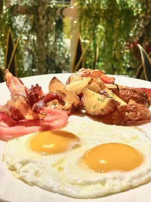 a plate of food with two fried eggs and meat at Leslie Hotel Ocean Drive in Miami Beach