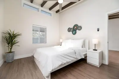 a white bedroom with a bed and a plant at The Hideaway at Lake Ridge 3 in Fort Lauderdale