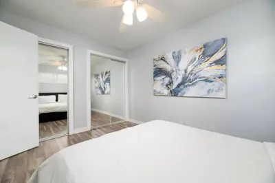 a white bedroom with a bed and a ceiling fan at The Palms at Middle River Terrace 3 in Fort Lauderdale