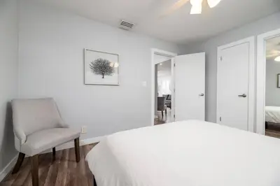 a white bedroom with a bed and a chair at The Palms at Middle River Terrace 1 in Fort Lauderdale