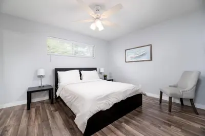 a white bedroom with a bed and a ceiling fan at The Palms at Middle River Terrace 1 in Fort Lauderdale
