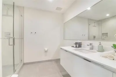 a white bathroom with two sinks and a shower at Rooftop Pool - Hot Tub - Gym - Near Beach in Hollywood