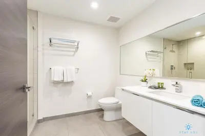 a white bathroom with a toilet and a sink at Hot tub & Rooftop pool - Near Beach in Hollywood