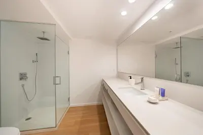 a bathroom with a shower and two sinks and a mirror at Beach Haus Residences in Bal Harbour