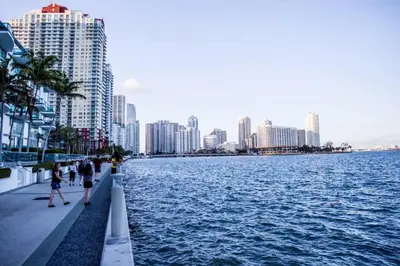 people walking on a sidewalk next to a body of water at 4BR APT with Bay View at Brickell, Free Parking in Miami