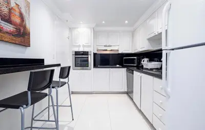 a white kitchen with white cabinets and black appliances at Beautiful 2 Bedroom Apartment on Hollywood Beach in Hollywood