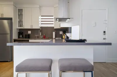 a kitchen with white cabinets and a counter with two stools at Blue Door Duplex Renovated Parking and Designed in Cutler Bay