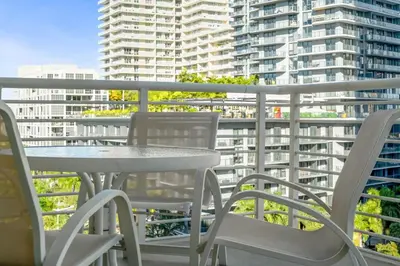 a table and chairs on a balcony with a large building at City Condo in Midtown Wynwood with pool and parking in Miami
