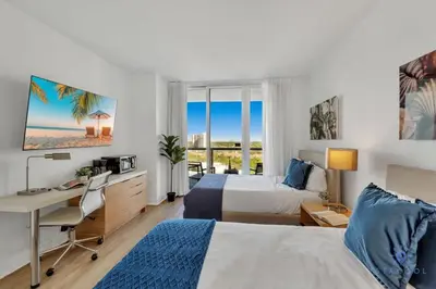 a hotel room with two beds and a desk at Infinite Views with Amazing Pool plus Gym, Near Beach in Hallandale Beach