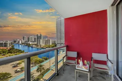 a balcony with two chairs and a red wall at Infinite Views with Amazing Pool plus Gym, Near Beach in Hallandale Beach