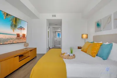 a bedroom with a large bed and a yellow rug at Infinite Views, Amazing Pool, Gym, Near Beach in Hallandale Beach