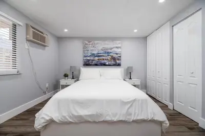 a white bedroom with a white bed and two white cabinets at Shell on the Beach 107 - RENOVATED in Hollywood
