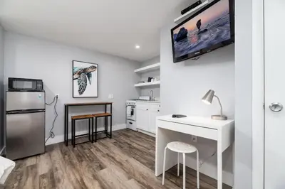 a white kitchen with a desk and a tv on the wall at Shell on the Beach 107 - RENOVATED in Hollywood