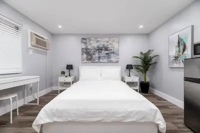 a white bedroom with a white bed and two tables at Shell on the Beach 105 - RENOVATED in Hollywood