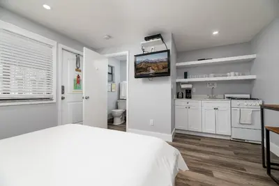 a white bedroom with a bed and a kitchen at Shell on the Beach 106 - RENOVATED in Hollywood