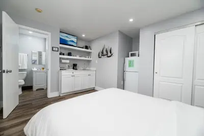 a white bedroom with a white bed and a kitchen at Shell on the Beach 102 - RENOVATED in Hollywood